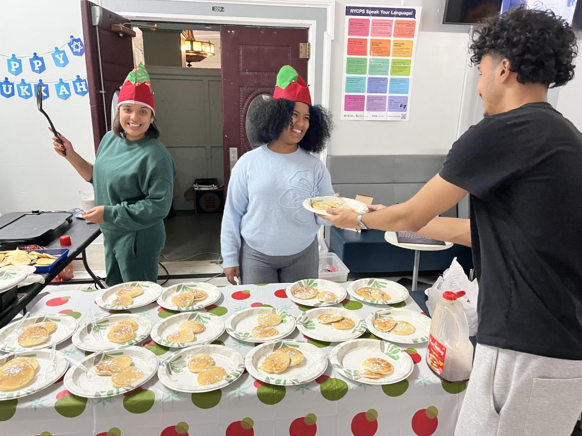 TCA senior Eddie Ricardo Lopez gets pancakes and a smile from staff member Nicole Hernandez.  Ms. Melo stands ready to flip the next batch.